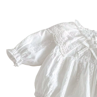 Angled view highlighting the lace shoulder trim and gathered long bishop sleeve on a white baby romper.