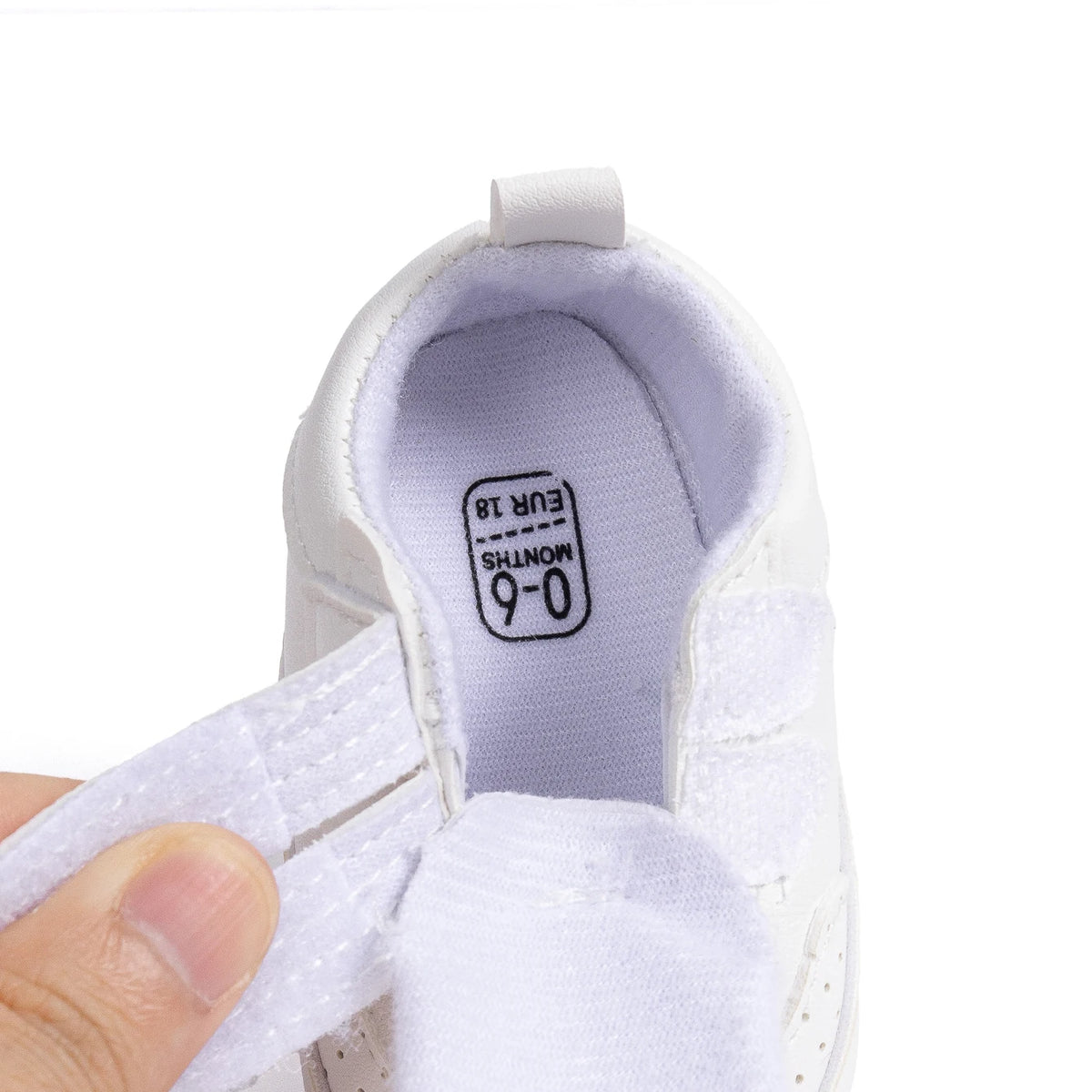 Close-up of the interior of a white infant sneaker showing the soft lining, wide opening, and size tag.
