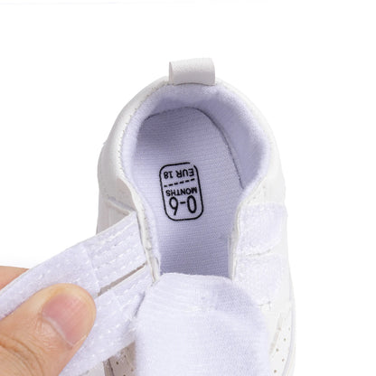 Close-up of the interior of a white infant sneaker showing the soft lining, wide opening, and size tag.