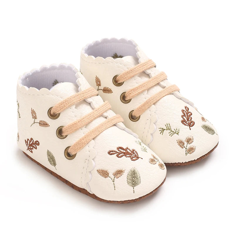 Pair of white boho embroidered baby girl booties with scalloped edges.