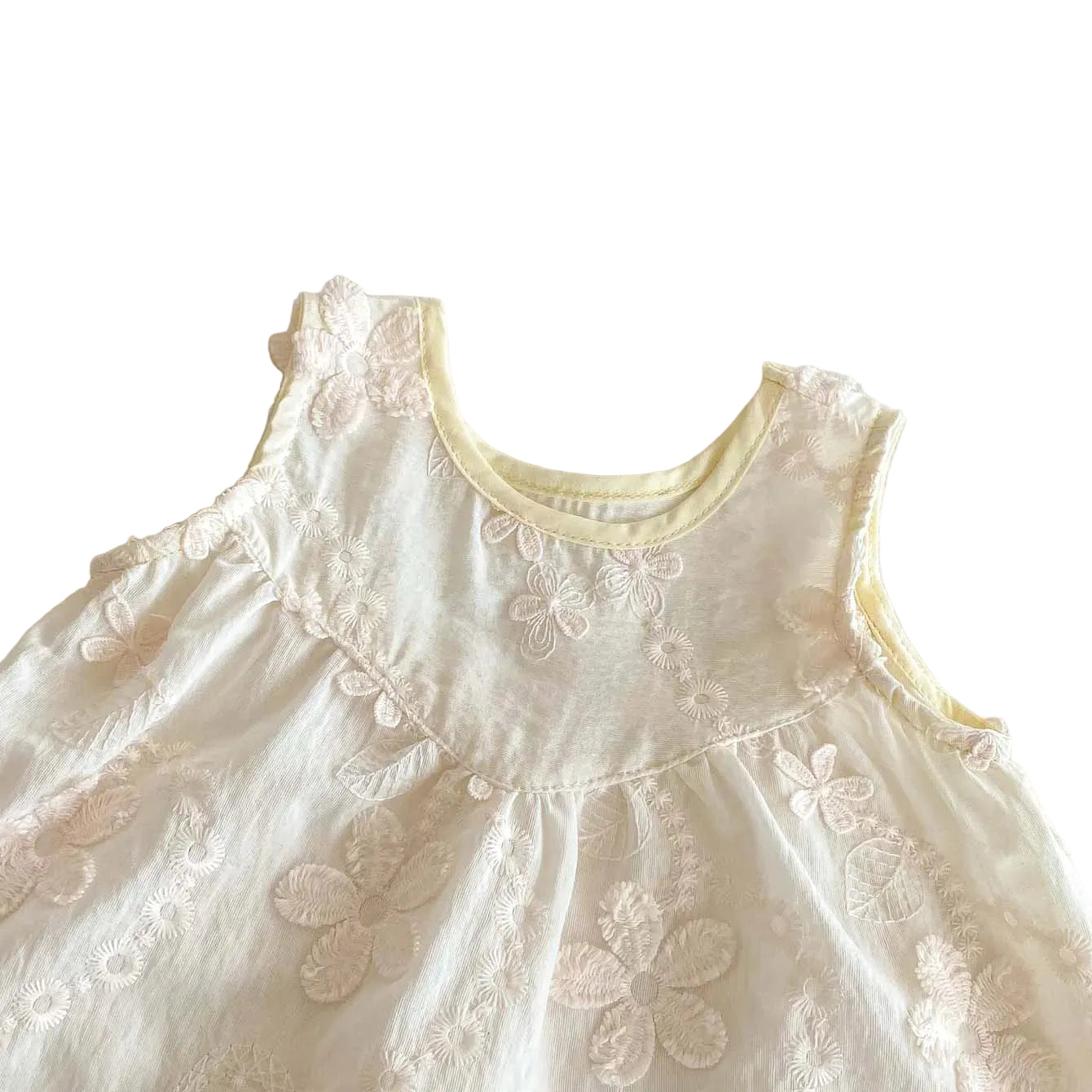 Close-up detail of the rounded neckline and delicate 3D floral embroidery on a white sleeveless baby tunic.