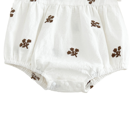 Close-up of the bottom snap area on the white baby romper.