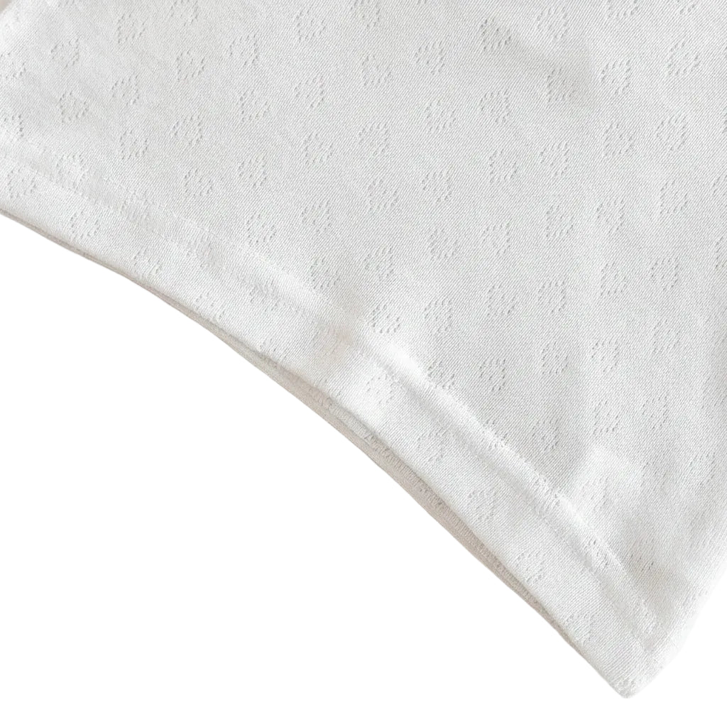 Clean close-up of the bottom hemline and quality stitching of the white short-sleeve baby shirt.