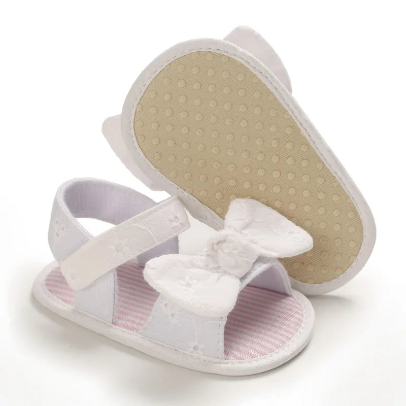 White infant pre-walker sandals showing the soft anti-slip dotted cotton sole and hook-and-loop strap.