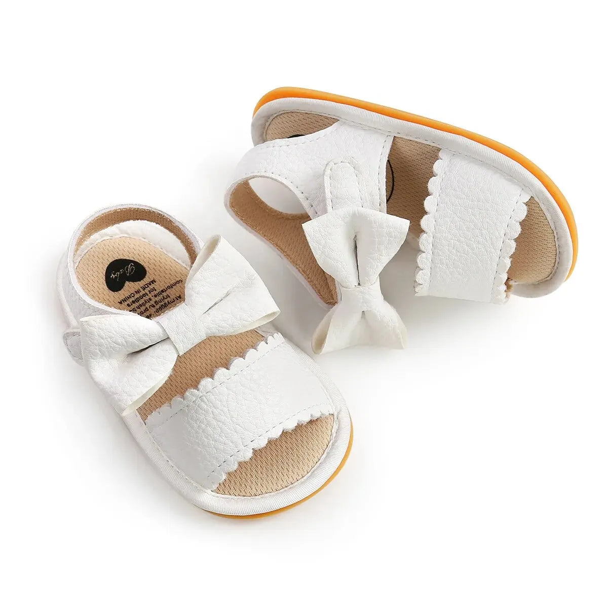 Pair of white leather infant girl walking sandals with a secure ankle support strap and scalloped textured detailing.