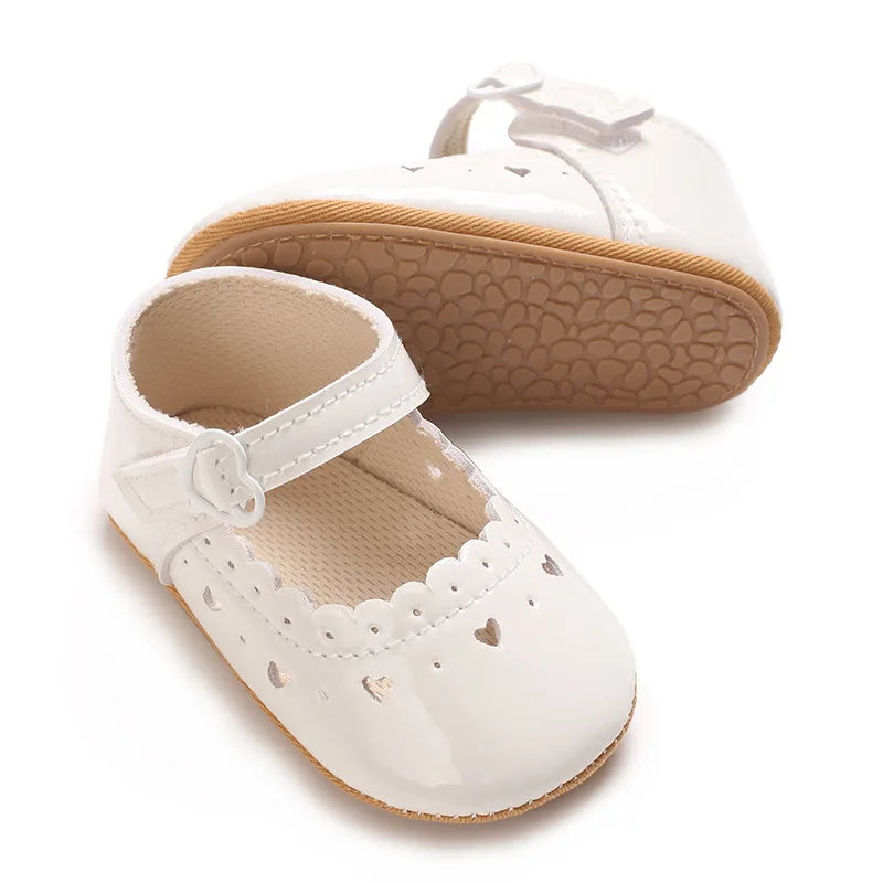 Pair of white baby girl pre-walker shoes displaying flexible bottom sole.