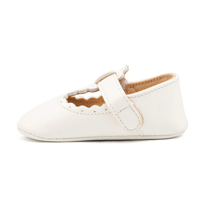 Side profile view of a single white baby girl soft sole T-strap shoe.