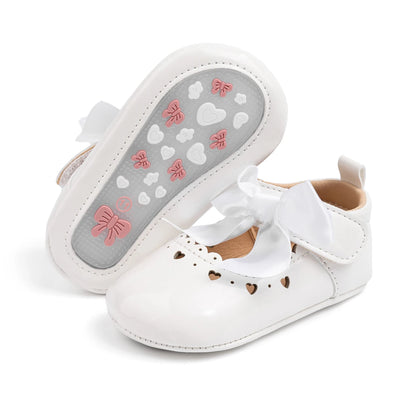 Bottom of a white baby shoe displaying the flexible PVC anti-slip sole with grip patterns for first walkers.