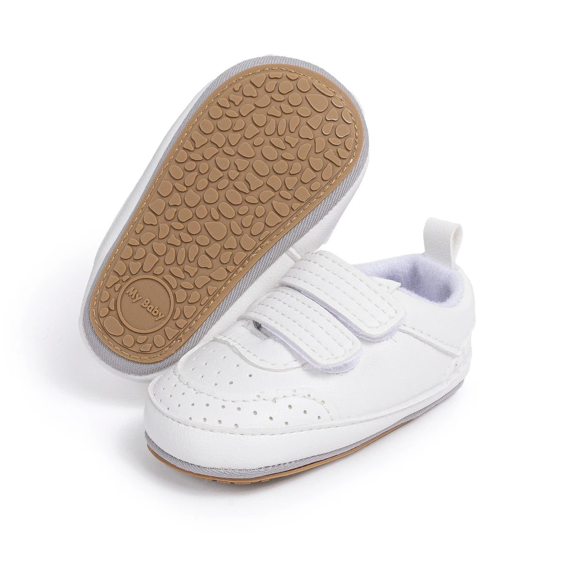 Pair of white baby sneakers with one resting on its side to display the flexible brown anti-slip sole.