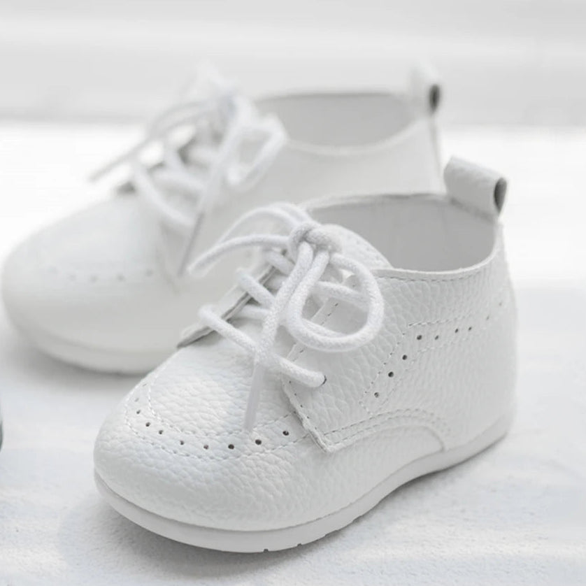 A pair of Kidsely white pebbled faux leather toddler brogues angled beautifully on a bright surface.