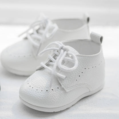 A pair of Kidsely white pebbled faux leather toddler brogues angled beautifully on a bright surface.