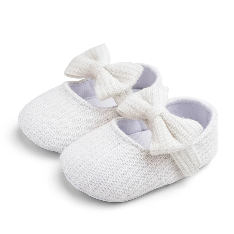 Pair of white ribbed knit Mary Jane crib shoes with front bows.