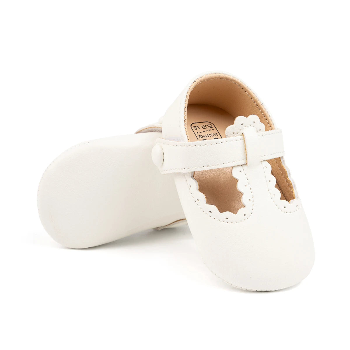 Pair of white baby girl soft sole crib shoes, with one resting on its side.