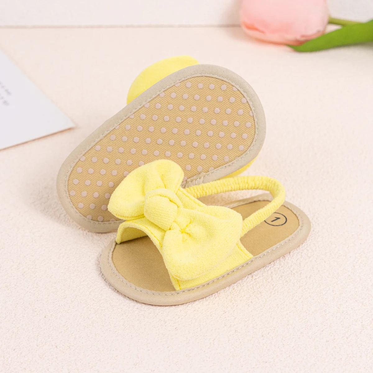 Pair of bright yellow baby girl soft sole sandals with an oversized soft brushed fabric bow.
