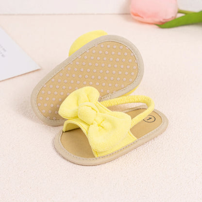 Pair of bright yellow baby girl soft sole sandals with an oversized soft brushed fabric bow.