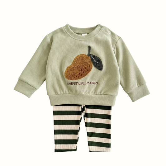 Mint green baby sweatshirt featuring a textured mango fruit patch and text "Sweet Like Mango," paired with dark green and cream striped pants.