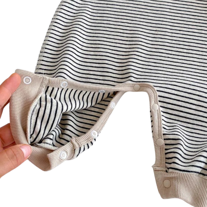 Close-up showing the inside of the Oat & Onyx baby romper with the covered snap buttons opened at the crotch for easy diaper changes.