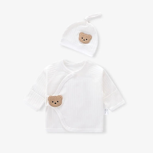 Flat lay of cream white newborn ribbed kimono top and matching knot hat featuring a textured teddy bear patch.