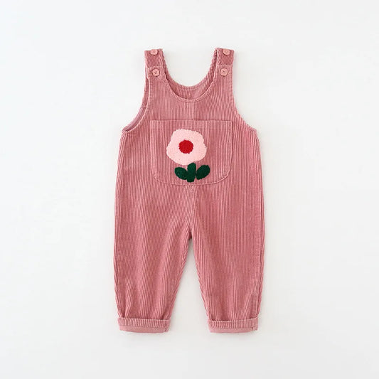 Flat lay of two toddler girls corduroy overalls in Petal Pink and Toasted Oat with a 3D flower patch on the front pocket, sizes 9M to 4T