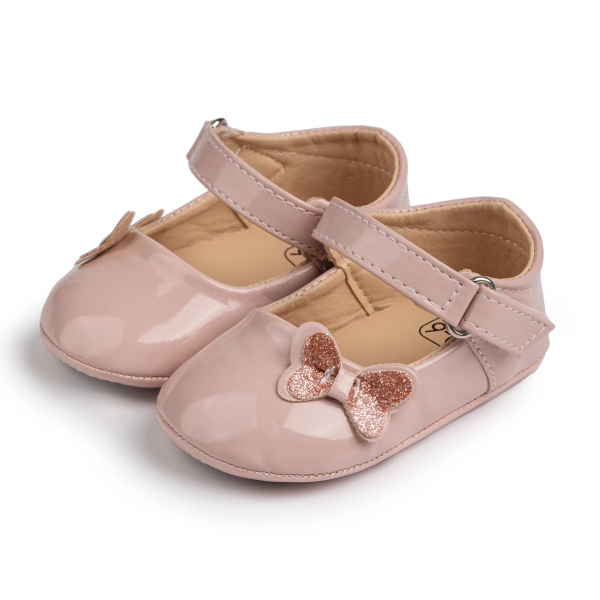 close-up of shiny pink patent baby girl mary jane shoes featuring a glitter butterfly bow and adjustable strap