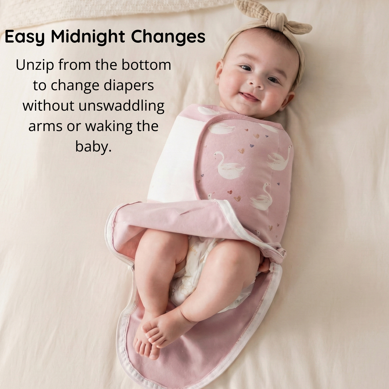 Newborn baby in pink swan swaddle showing easy midnight diaper change feature with bottom zipper access to keep arms securely swaddled.