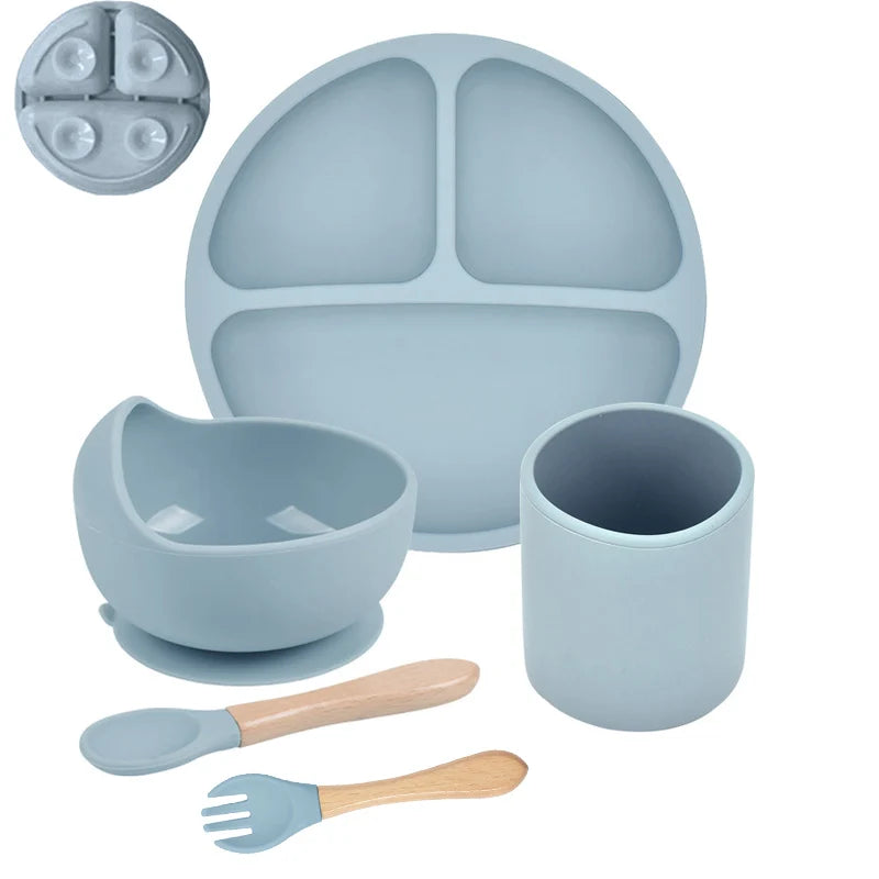 Blue silicone dining set with plate, bowl, cup, spoon, and fork on a white background