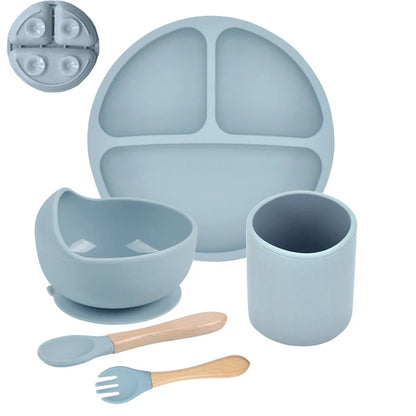 Blue silicone dining set with plate, bowl, cup, spoon, and fork on a white background