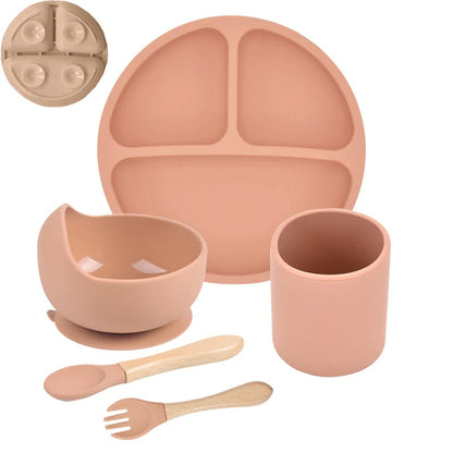 Orange children's silicone dinner set with plate, bowl, cup, spoon, and fork on a white background.