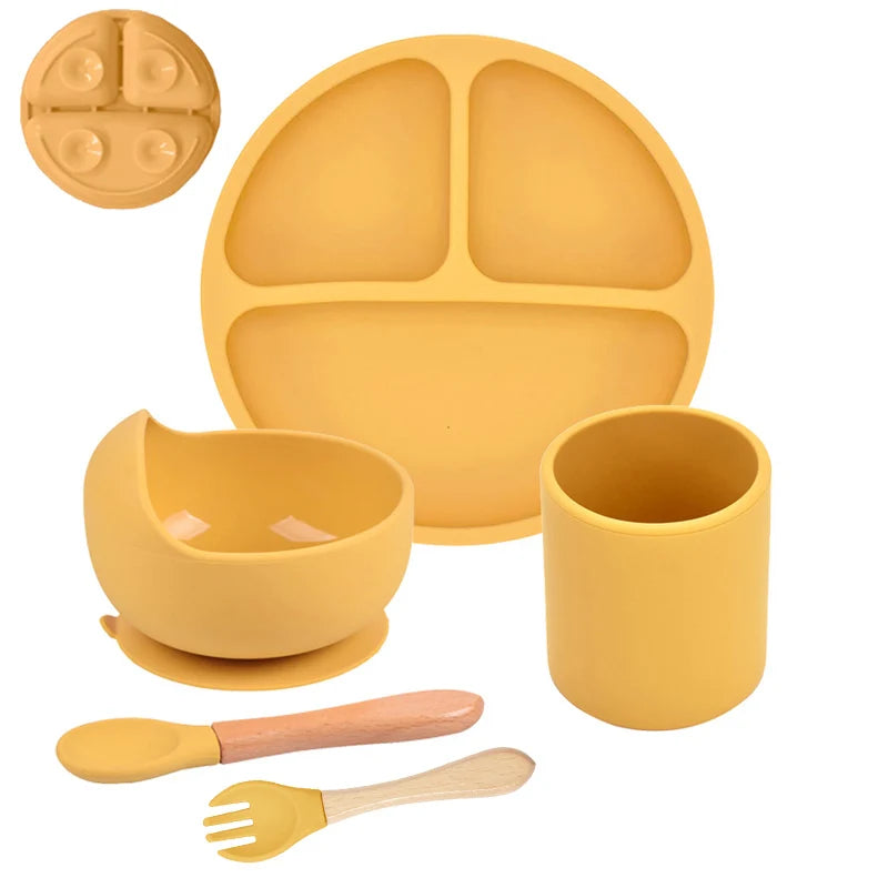 Yellow silicone dinner set with plate, bowl, cup, spoon, and fork on a white background