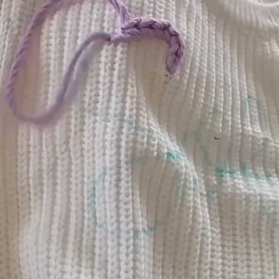 Video demonstration of hand-embroidered custom name stitching on a baby knit sweater