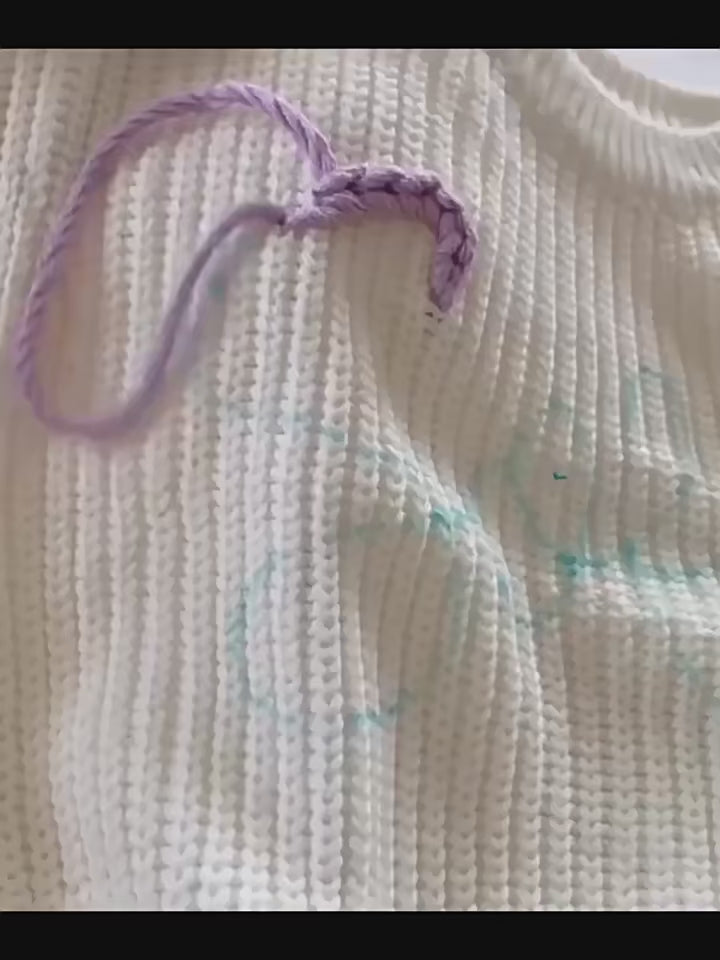 Video demonstration of hand-embroidered custom name stitching on a baby knit sweater
