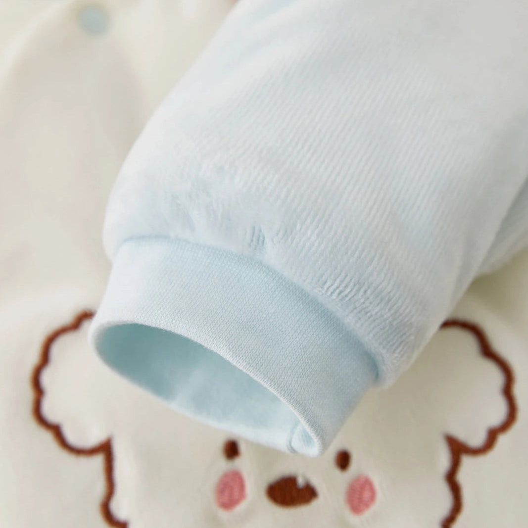 Close-up detail of the soft light blue ribbed cuff on the sleeve of the quilted baby romper.