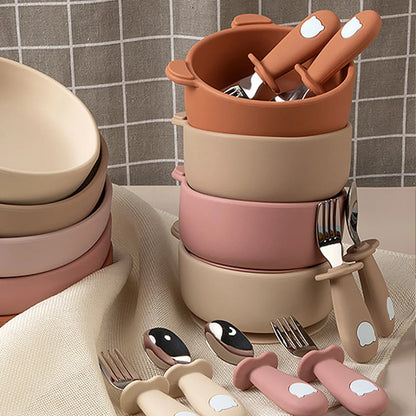 Set of children's cutlery and bowls in pastel colors on a neutral background
