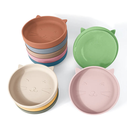 Top-down view of a silicone baby plate shaped like a cat head with three divided food sections and a suction base.