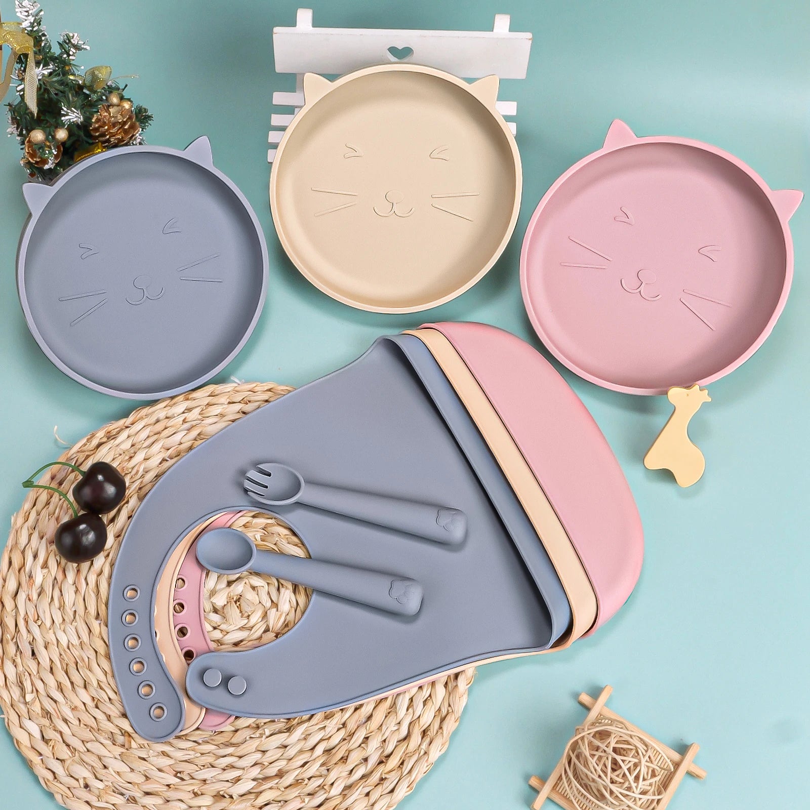 Set of colorful children's plates and cutlery with cat designs on a light blue background.