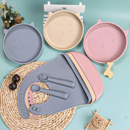Set of colorful children's plates and cutlery with cat designs on a light blue background.