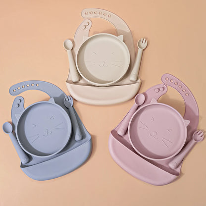 4-piece silicone feeding set including a rectangular divided suction tray, bib with pocket, and matching fork and spoon.