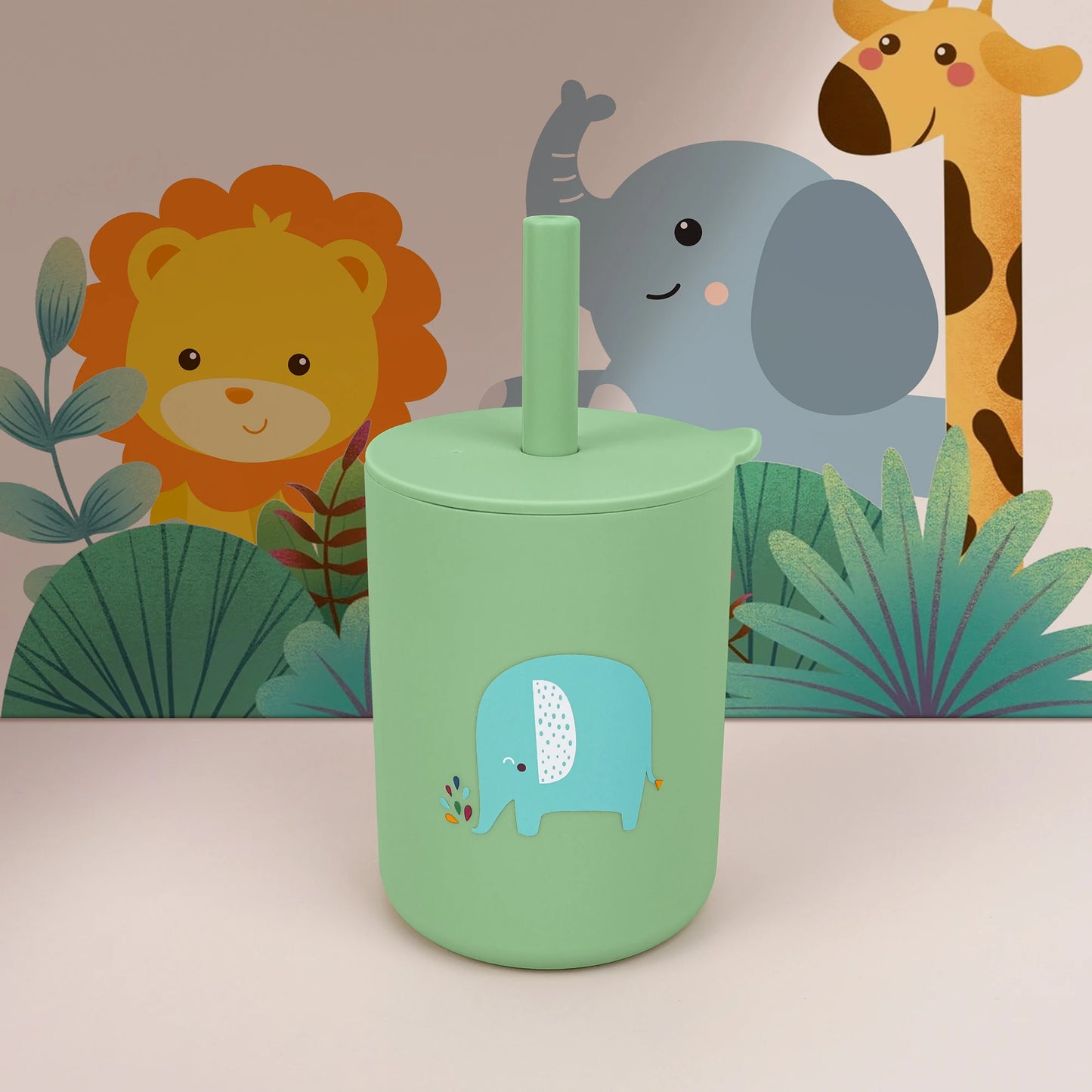 Green tumbler with a blue elephant design in front of cartoon animals on a beige background