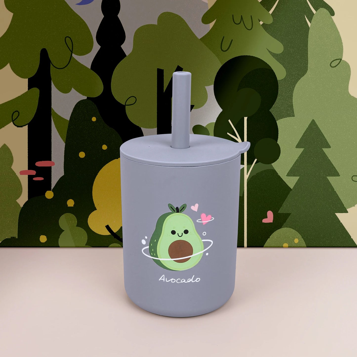 Gray tumbler with avocado design against a forest background