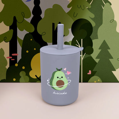 Gray tumbler with avocado design against a forest background