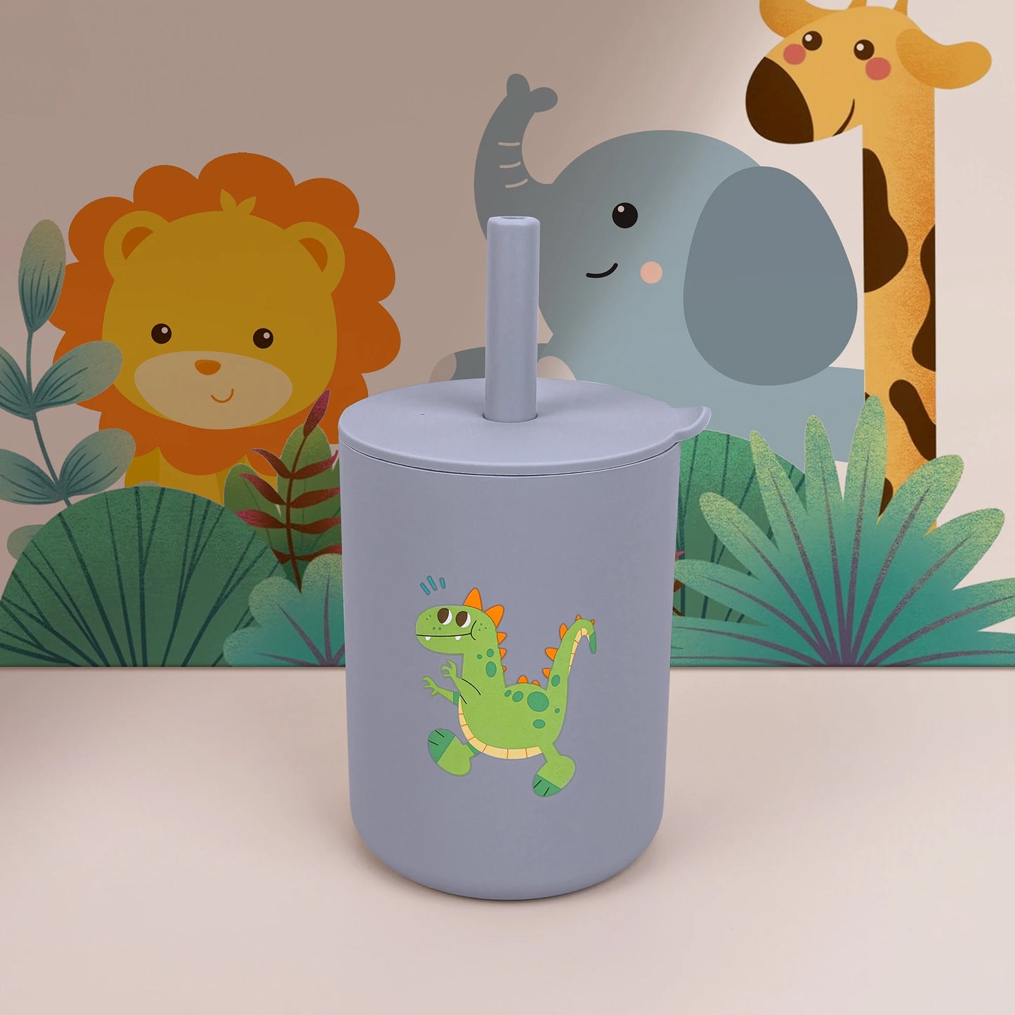 Gray tumbler with a green dinosaur design in front of a children's wall mural featuring animals and plants.