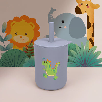 Gray tumbler with a green dinosaur design in front of a children's wall mural featuring animals and plants.
