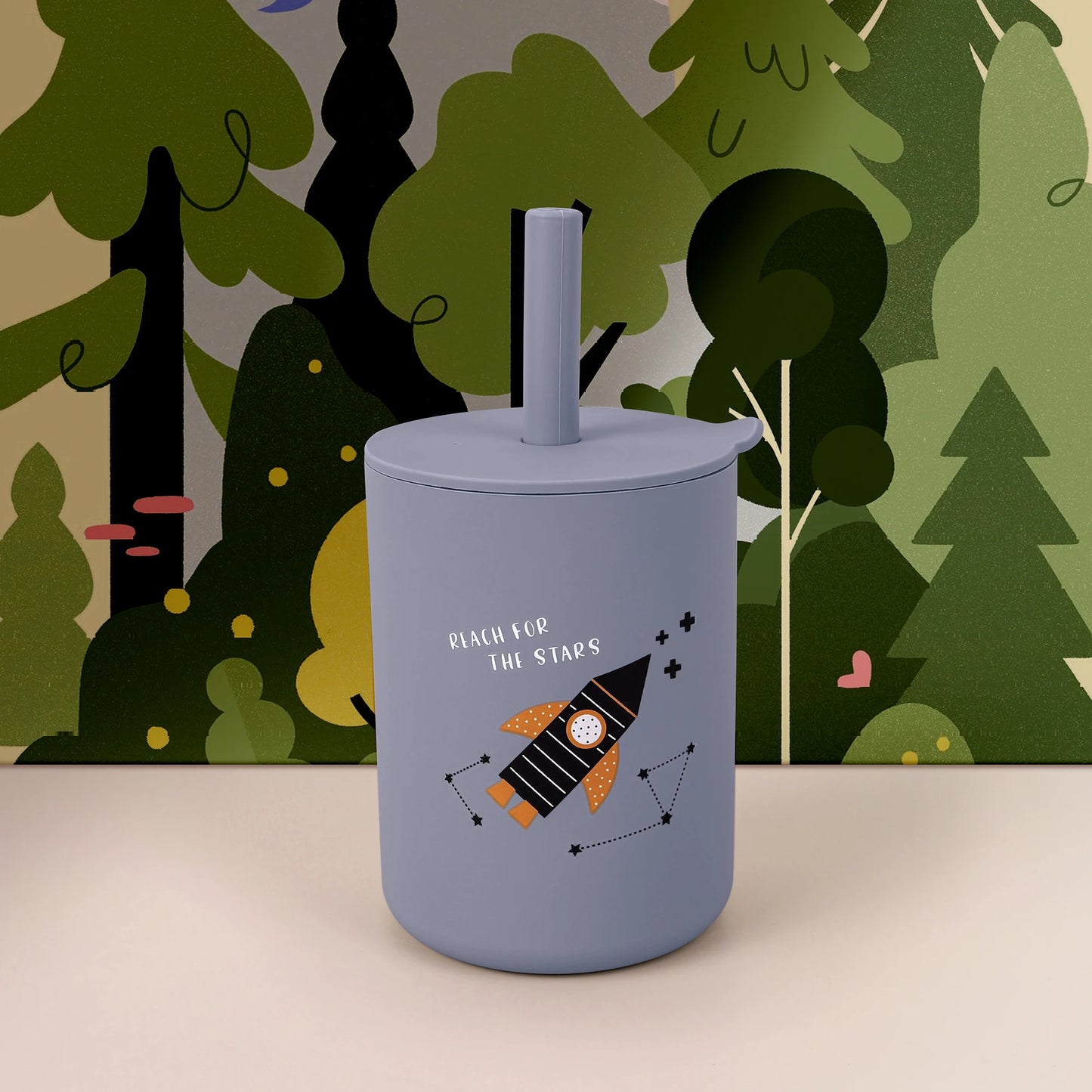 Blue tumbler with a space-themed design against a forest background