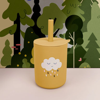 Yellow tumbler with a cloud design against a forest background