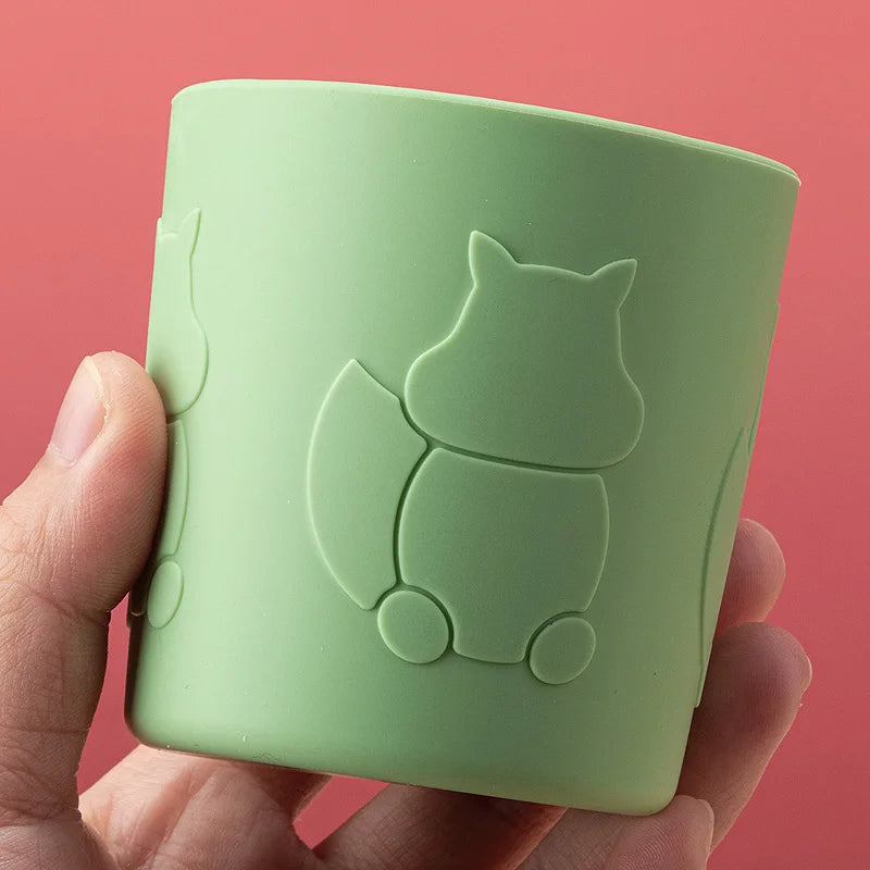 Green silicone cup with squirrel design held by a hand against a red background