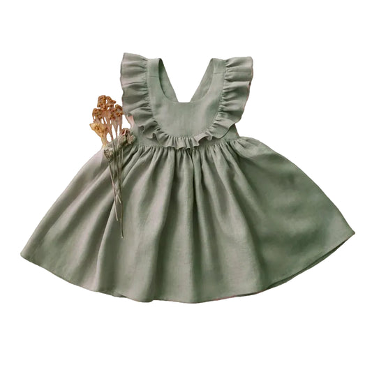 Front view of a sage green toddler girl linen cotton apron dress with ruffle straps and cross-back detail.